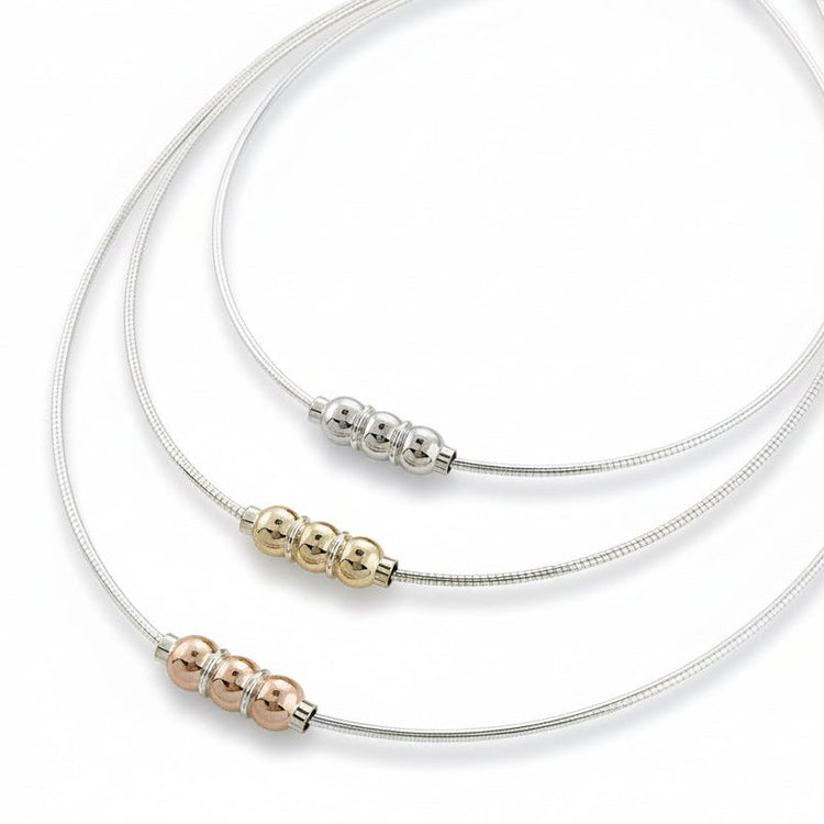 A collection of Cape Cod triple ball omega necklaces in silver with varying lengths, displayed on a flat surface.
