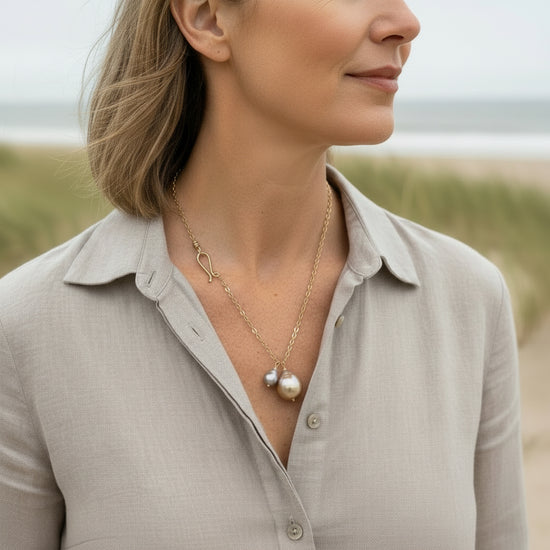 Woman wearing a gold necklace with a pearl pendant in a natural setting