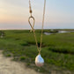 A baroque pearl long sea drop necklace with a gold-filled chain, displayed against an outdoor backdrop.