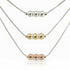 Three necklaces with different colored beads on a light gray background