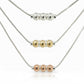 Three necklaces with different colored beads on a light gray background
