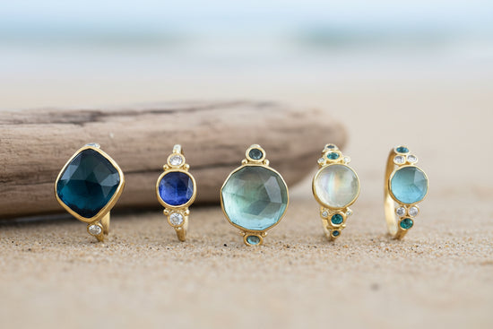 Aqua and gold gemstone rings on beach background