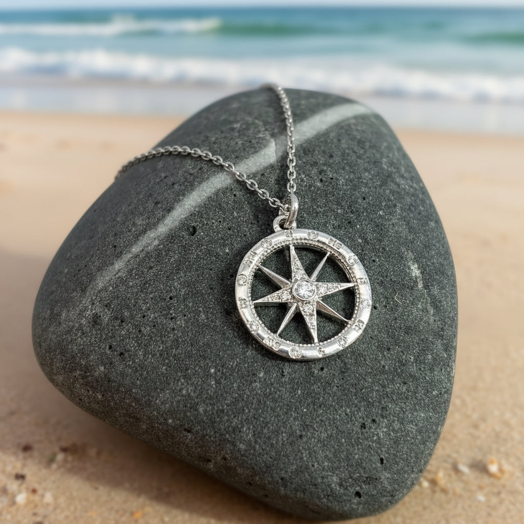 White gold and diamond compass pendant necklace on a dark stone surface