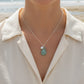 Necklace with an aquamarine eardrop pendant and white pearl and gray beads on model